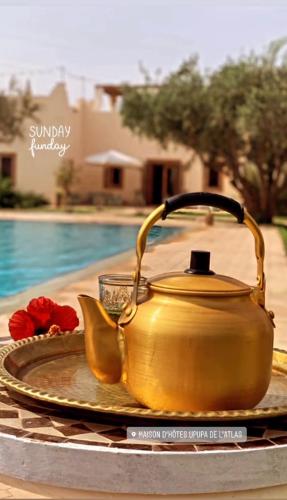 a gold tea kettle on a plate next to a pool at Upupa de l’Atlas in Marrakech