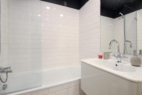 a white bathroom with a sink and a bath tub at Charming Studio in central Lisbon in Lisbon