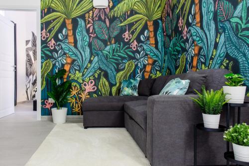 a living room with a couch and a tropical wallpaper at Tropical - Boutique Apartment in Gallipoli