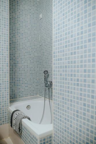 a blue tiled bathroom with a tub with a shower at 1909 Guesthouse in Kalavrita