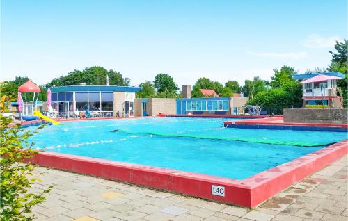 a large swimming pool with blue water in front of a building at 3 Bedroom Amazing Home In Heinkenszand in Heinkensand