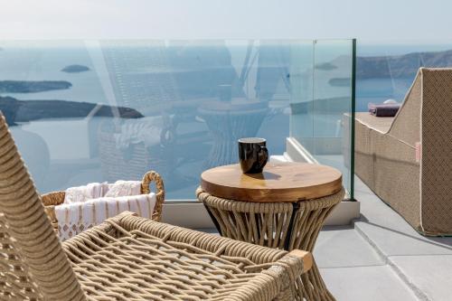 a table and chairs on a balcony with a cup on it at Kaleidoscope Imerovigli Suites in Imerovigli
