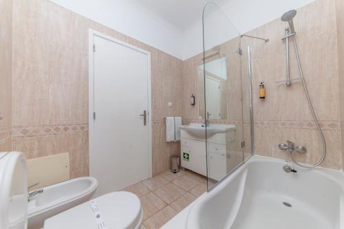 ein Badezimmer mit einer Badewanne, einem WC und einem Waschbecken in der Unterkunft Atalaia Sol Aparthotel - tennis & heated pool in winter in Lagos