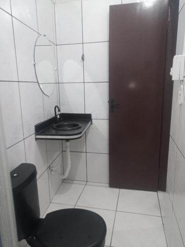 a bathroom with a toilet and a sink and a door at Pousada Recanto do Mar in Tutóia