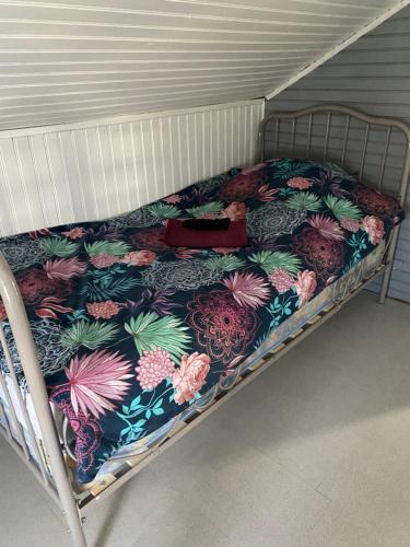 Una cama con un edredón de flores con un bolso. en Petite maison atypique animaux acceptés en Les Forges
