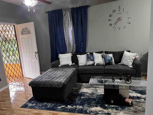 ein Wohnzimmer mit einem Sofa und einer Uhr an der Wand in der Unterkunft Cheerful VinAdas in Mandeville