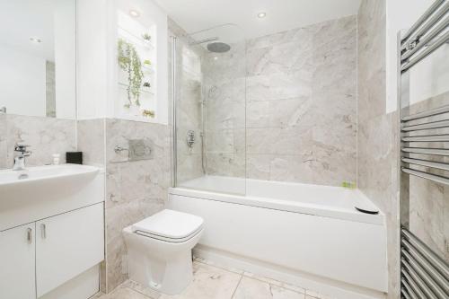 a bathroom with a white tub and a toilet and a sink at Cozy 1bedroom flat in Romford in Romford