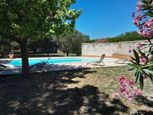 - une piscine avec deux chaises dans la cour dans l'établissement Villa provençale avec piscine et grand jardin, à Saint-Geniès-de-Comolas