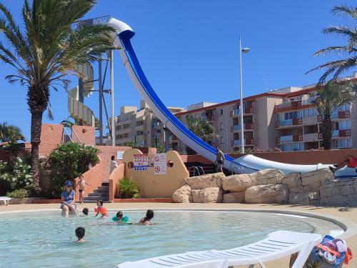 - un groupe de personnes dans une piscine avec toboggan dans l'établissement Mobil-home tout confort camping Mar Estang à Canet en roussillon, à Canet