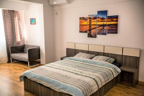 a bedroom with a bed and a chair at Apartament Mamaia Nord in Mamaia Nord