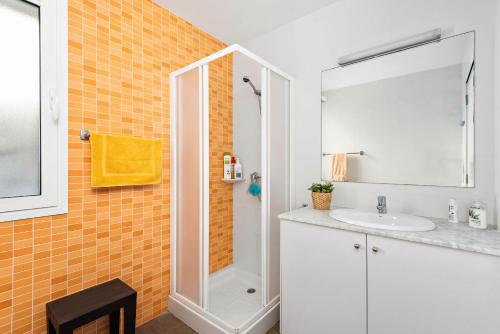 an orange tiled bathroom with a sink and a shower at Villa Sa Gavina - Addaia in Port d'Addaia