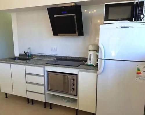 uma cozinha com um frigorífico branco e um micro-ondas em Azares departamentos en alquiler temporario em Valeria del Mar