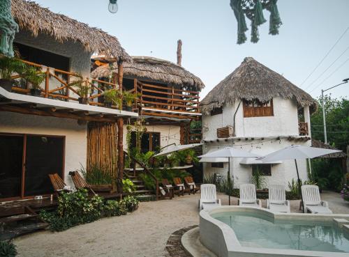 a house with a pool and chairs and an umbrella at Arte Sano Hotel - Adults only in Holbox Island