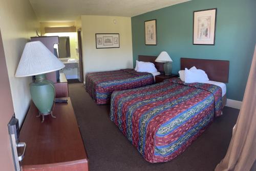 a hotel room with two beds and a lamp at Hilltop Inn Pittsburgh in Pittsburgh