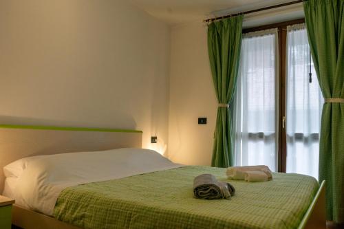 Schlafzimmer mit einem Bett mit grünen Vorhängen und einem Fenster in der Unterkunft Rosadira Vista Lago sulle Dolomiti in Auronzo di Cadore