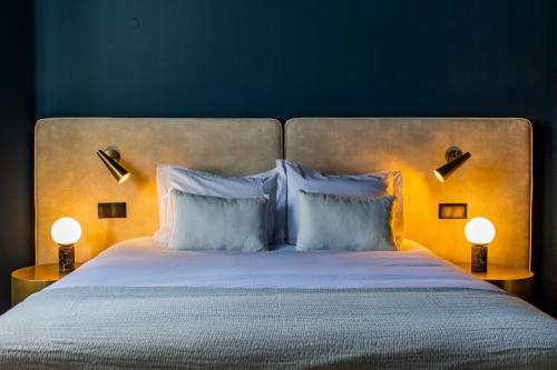 uma cama com almofadas e dois candeeiros ao lado em Regras 45 Building A by LovelyStay no Porto