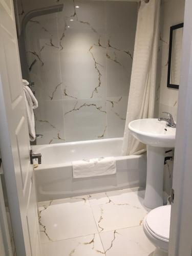 ein Badezimmer mit einem Waschbecken, einer Badewanne und einem WC in der Unterkunft Beausejour Hotel Apartments/Hotel Dorval in Dorval