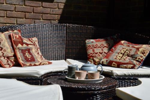 two wicker chairs with pillows and a table with cups at The Annex, Westerlands, Graffham in Graffham