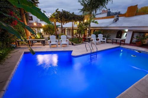 門多薩的住宿－Posada de Rosas，蓝色的游泳池配有白色的椅子和桌子