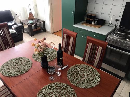 a dining room table with a bottle of wine and flowers on it at Apartman Lana in Bajina Bašta