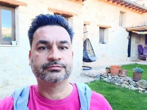 a man with blue hair standing in front of a house at La Casona de Castilnovo - Gay Men Only in Valdesaz