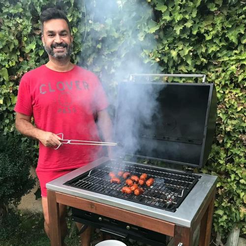 a man is cooking food on a grill at La Casona de Castilnovo - Gay Men Only in Valdesaz