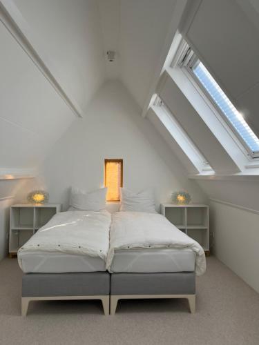 een slaapkamer met een bed op een zolder met dakramen bij Aventure in Noordwijk