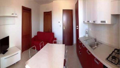 una cucina con divano rosso in una camera di Regina Apartments ad Alghero