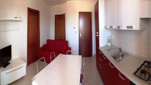 a kitchen with a red couch in a room at Regina Apartments in Alghero
