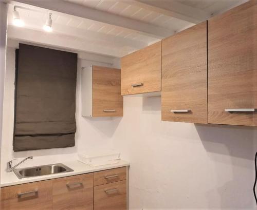 una cocina con armarios de madera y fregadero en Windmill House Mykonos, en Megali Ammos