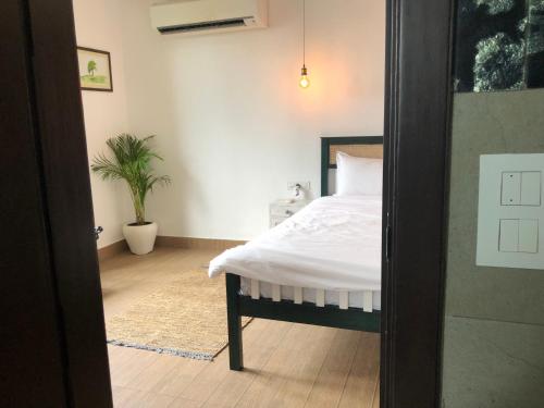 a bedroom with a bed with white sheets and a plant at Avatar Living@ Greater Kailash 2 in New Delhi