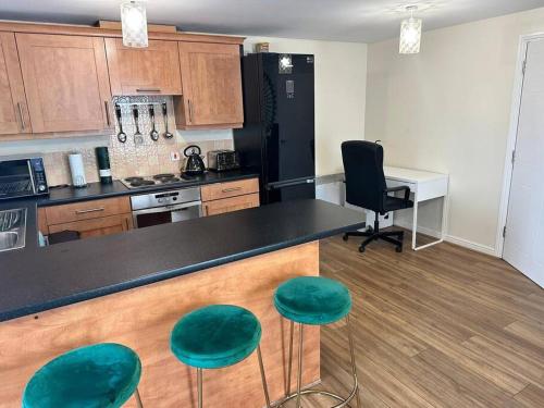 a kitchen with a black counter and green stools at Abbey Wood Luxurious Flat. in Abbey Wood