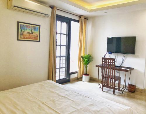 a bedroom with a bed and a desk with a television at Avatar Living@ Greater Kailash 2 in New Delhi