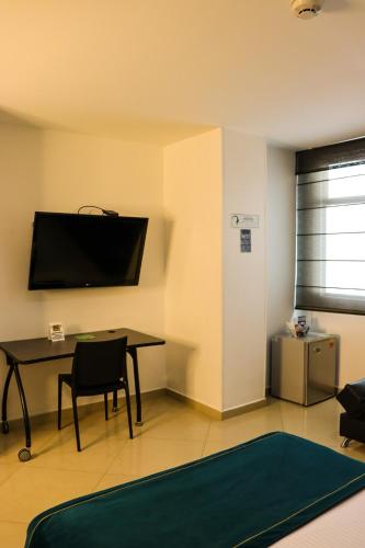 a living room with a table and a tv on the wall at hotel medellin gold in Medellín