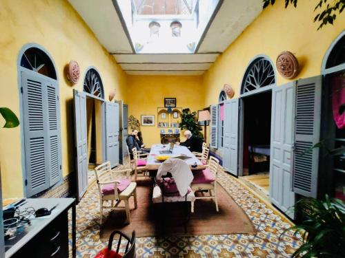 a dining room with a table and chairs and windows at La Maison Haute Larache Morocco in Larache