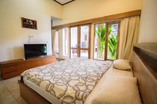 een slaapkamer met een groot bed en een televisie bij The Janan Villa in Sanur