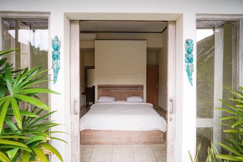 a bedroom with a bed in a room with plants at The Janan Villa in Sanur