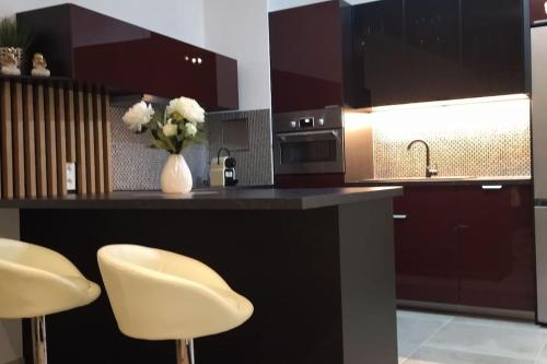 a kitchen with a counter with two white chairs at City Center Apartment III in Nitra
