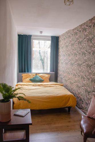 a bedroom with a bed with a yellow bedspread at Hostel Barbarossa in Nijmegen