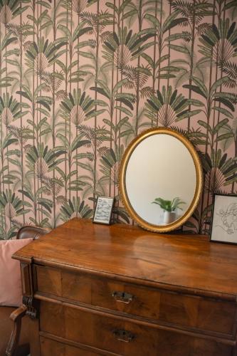 a mirror on top of a dresser with a wallpaper at Hostel Barbarossa in Nijmegen