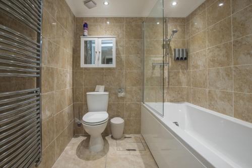 a bathroom with a toilet and a tub and a shower at Riverside Central Kingston Flat 1B in Surbiton