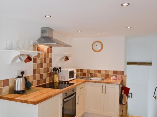 a kitchen with white cabinets and a clock on the wall at The Briar in Idridgehay