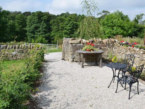 a table and chairs in front of a stone wall at The Briar in Idridgehay