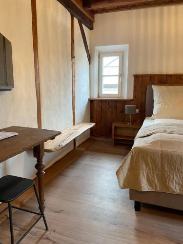a bedroom with a bed and a table and a window at Altes Rathaus in Schwaigern