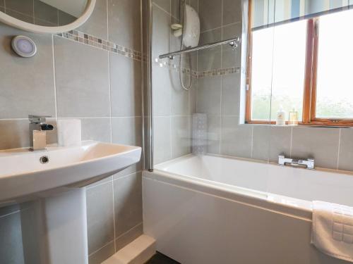 a bathroom with a sink and a bath tub and a window at Hilston in Rhyl