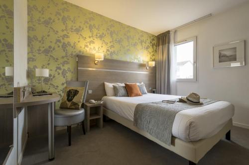 una habitación de hotel con una cama grande y una silla en Logis Beaujoire Hôtel, en Nantes