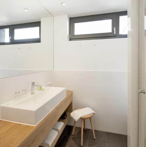 a white bathroom with a sink and a mirror at Hotel M120 in Munich