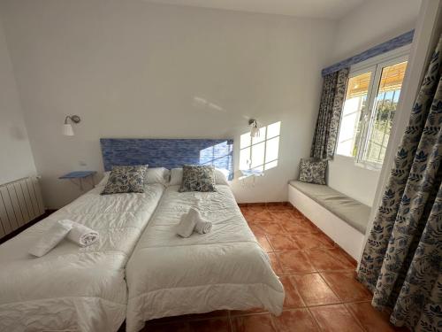 a bedroom with two beds and a couch and windows at CORTIJO RURAL FLOR DE CAZALLA in Cazalla de la Sierra