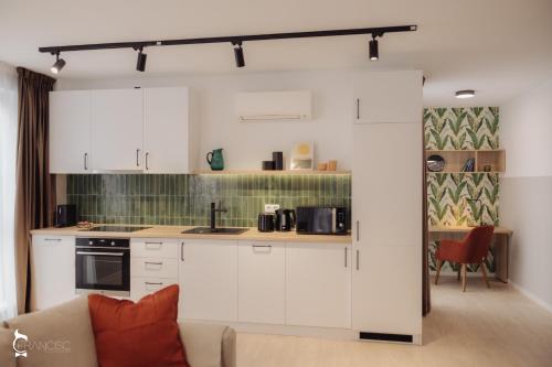 a kitchen with white cabinets and a couch in a room at ZEN Garden Apartments in Cluj-Napoca