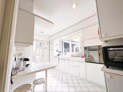 a kitchen with white cabinets and a table and a tv at Casa Via Saleggi 10 in Ascona